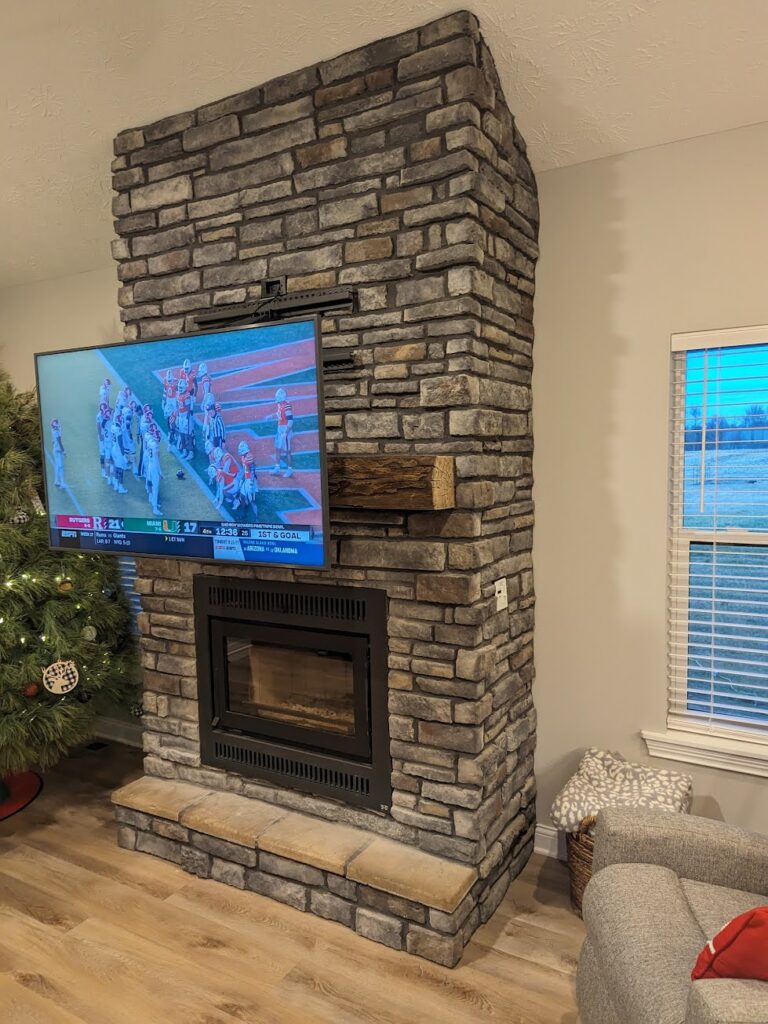 Expert TV installation on an irregular stone fireplace in Louisville, KY, featuring a complex pull-down Mantelmount, overcoming structural challenges.