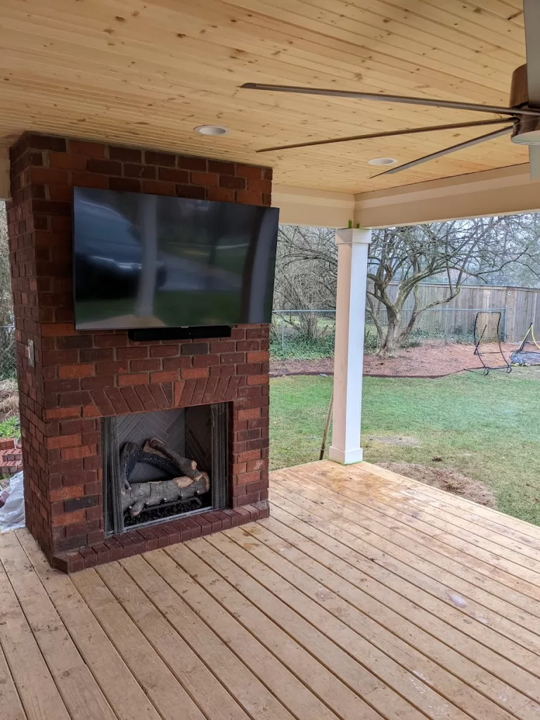 Outdoor TV mounted on brick fireplace in Louisville, KY, with full-motion mount and soundbar. | TV Mounting Louisville Kentucky