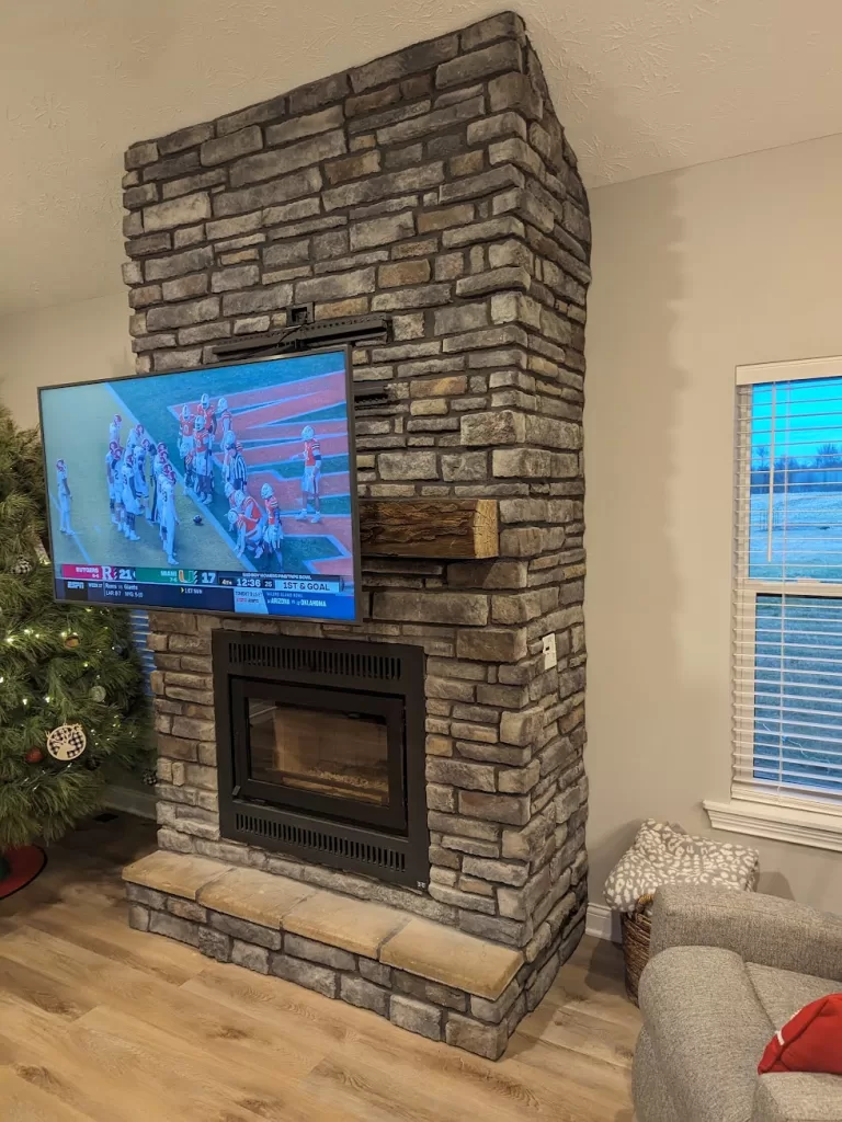 Expert TV installation on an irregular stone fireplace in Louisville, KY, featuring a complex pull-down Mantelmount, overcoming structural challenges. | TV Mounting Louisville Kentucky